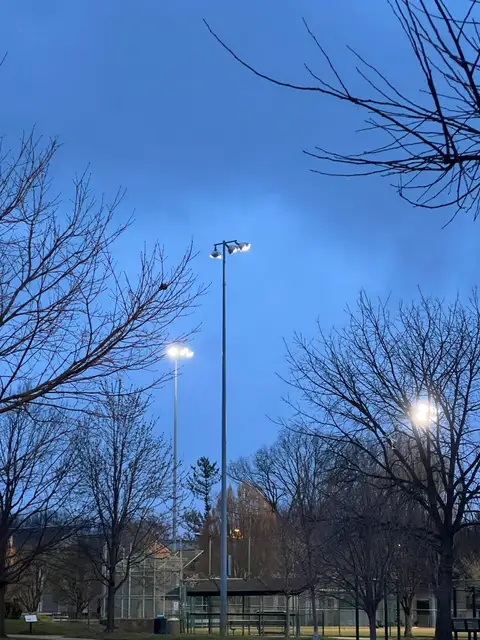 Stadium lights ignite the twilight sky.